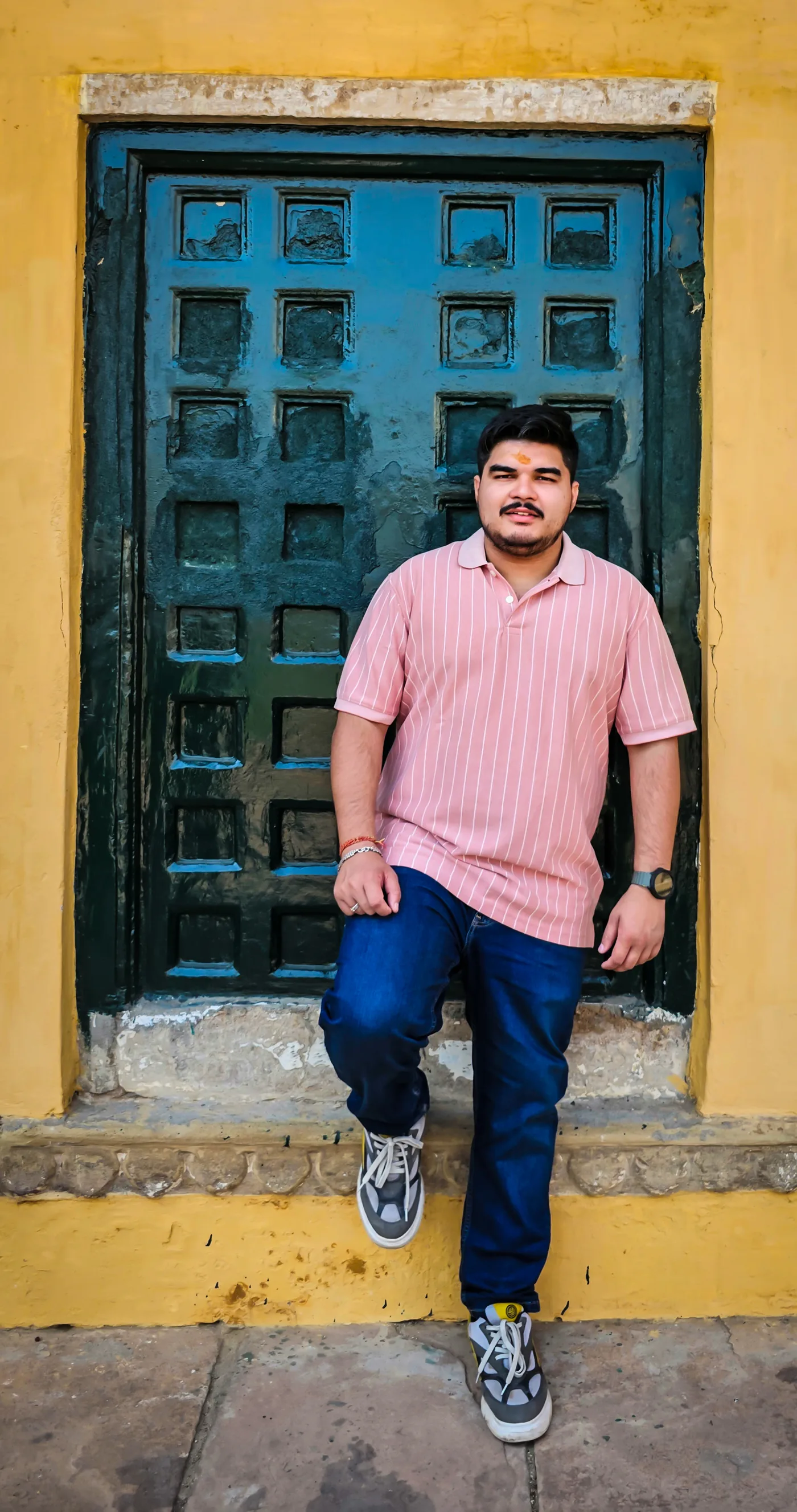 Shubhankar standing by a blue doorway framed by yellow walls